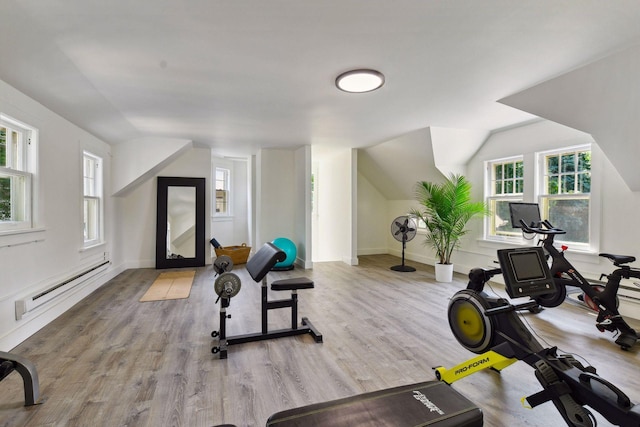 workout room with baseboards, vaulted ceiling, a baseboard radiator, and wood finished floors