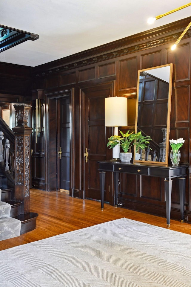 interior space with ornamental molding, light wood-type flooring, and wood walls