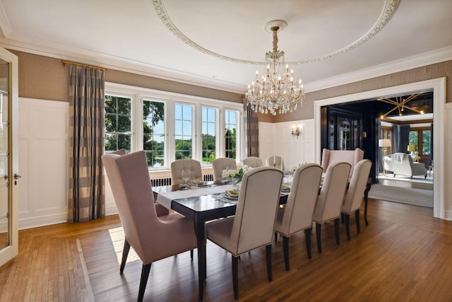 dining space with crown molding, a chandelier, a decorative wall, and wood-type flooring