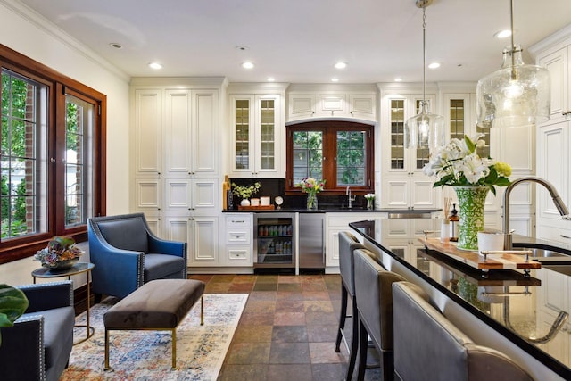 bar with wine cooler, sink, decorative light fixtures, white cabinetry, and tasteful backsplash