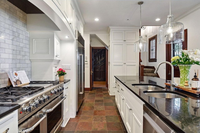 kitchen with a sink, dark stone counters, pendant lighting, white cabinetry, and high quality appliances