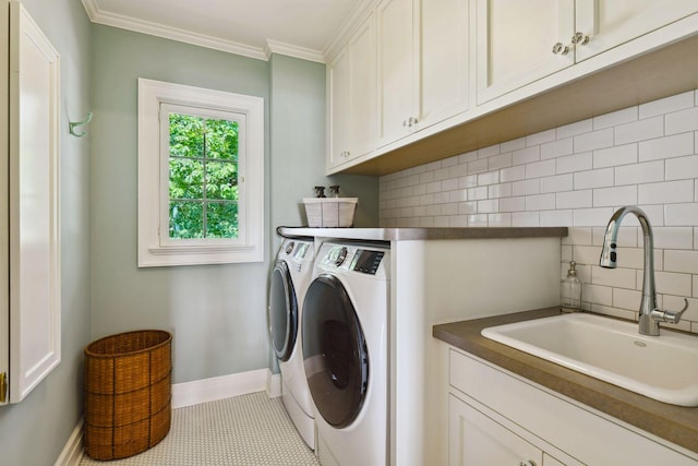 washroom featuring baseboards, washer and dryer, a sink, crown molding, and cabinet space