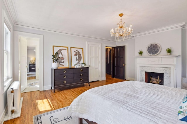 bedroom featuring radiator heating unit, crown molding, hardwood / wood-style flooring, a premium fireplace, and an inviting chandelier