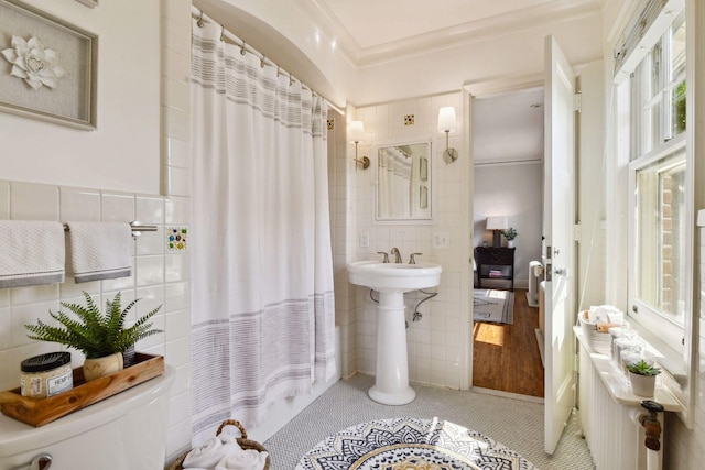full bathroom featuring toilet, tile walls, crown molding, and plenty of natural light