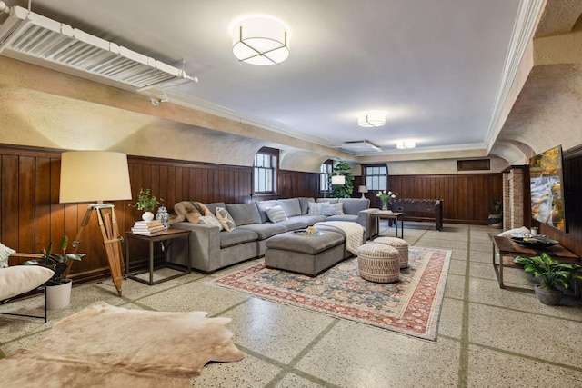 living room with crown molding and wood walls