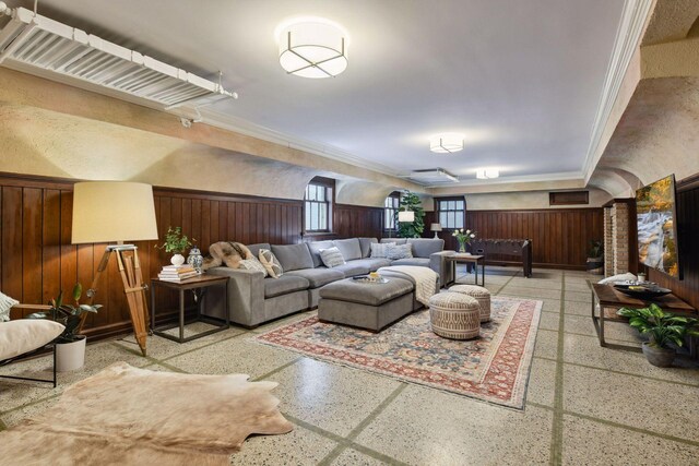 living area with crown molding, wooden walls, speckled floor, and a wainscoted wall