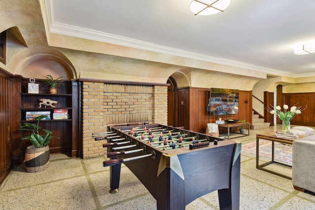 rec room with arched walkways, ornamental molding, and speckled floor
