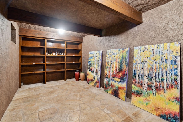 wine room featuring beamed ceiling