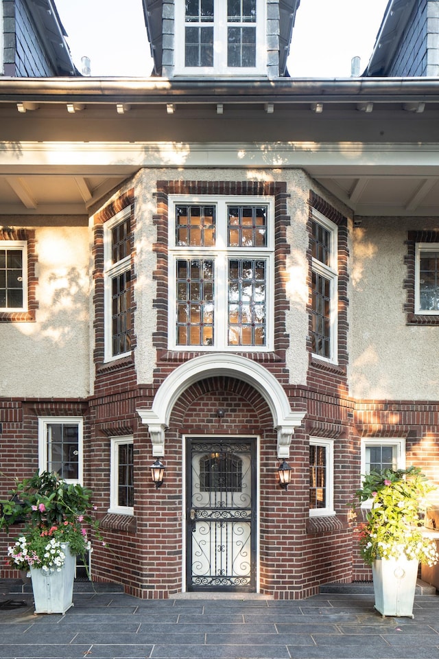 view of exterior entry featuring stucco siding and brick siding