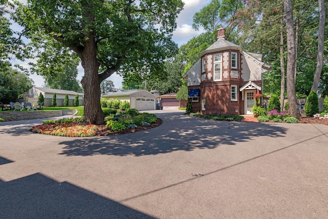 view of home's exterior featuring a chimney, an outdoor structure, brick siding, and a garage