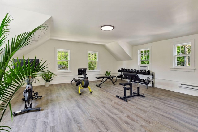 workout area with light hardwood / wood-style floors, a baseboard radiator, and vaulted ceiling