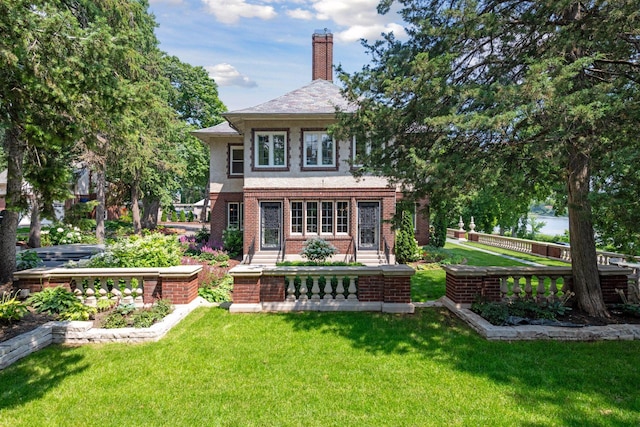 back of house featuring a yard, brick siding, a chimney, and fence