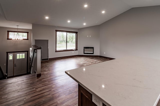 unfurnished living room with an inviting chandelier and dark wood-type flooring