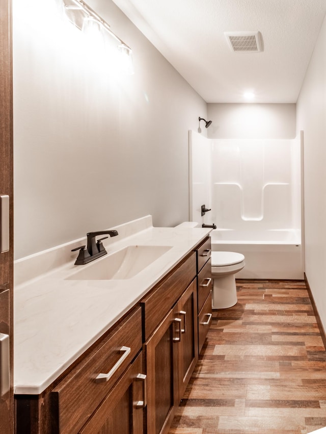 full bathroom featuring vanity, hardwood / wood-style flooring,  shower combination, and toilet