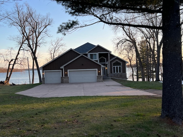 view of front of property featuring a front lawn, a garage, and a water view