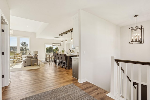 corridor featuring sink, an inviting chandelier, and hardwood / wood-style floors