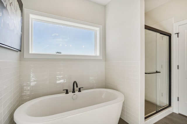 bathroom featuring tile walls, hardwood / wood-style floors, and shower with separate bathtub