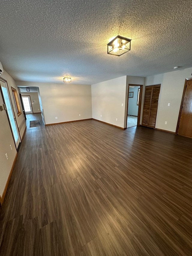 unfurnished living room with a textured ceiling and dark hardwood / wood-style floors