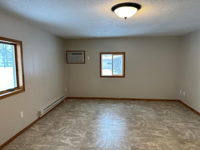 empty room featuring a healthy amount of sunlight, an AC wall unit, a textured ceiling, and a baseboard radiator