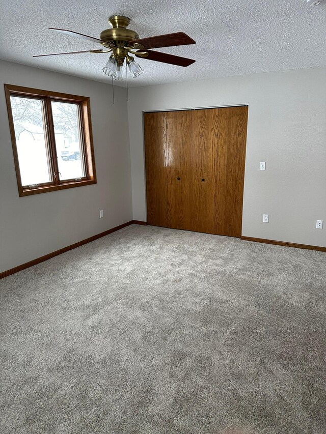 unfurnished bedroom with carpet flooring, ceiling fan, a closet, and a textured ceiling