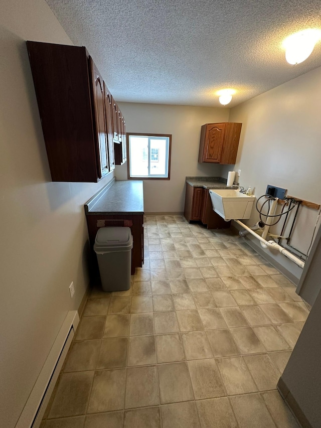 kitchen with baseboard heating, sink, and a textured ceiling