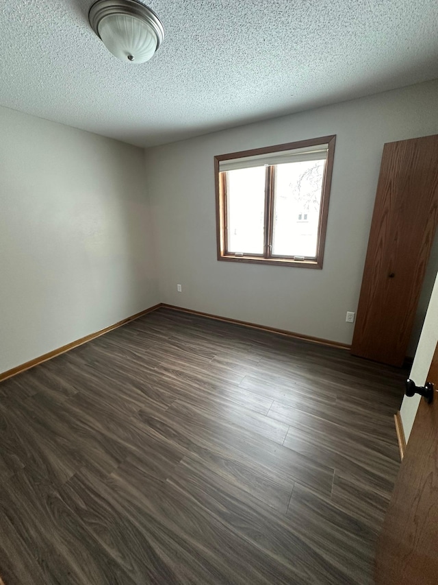 spare room featuring a textured ceiling and dark wood-type flooring