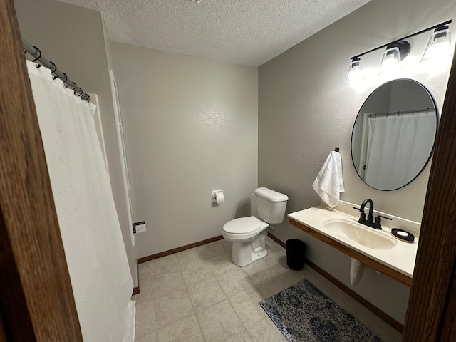 bathroom featuring a textured ceiling, toilet, and sink