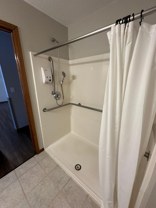 bathroom with a textured ceiling, tile patterned floors, and walk in shower