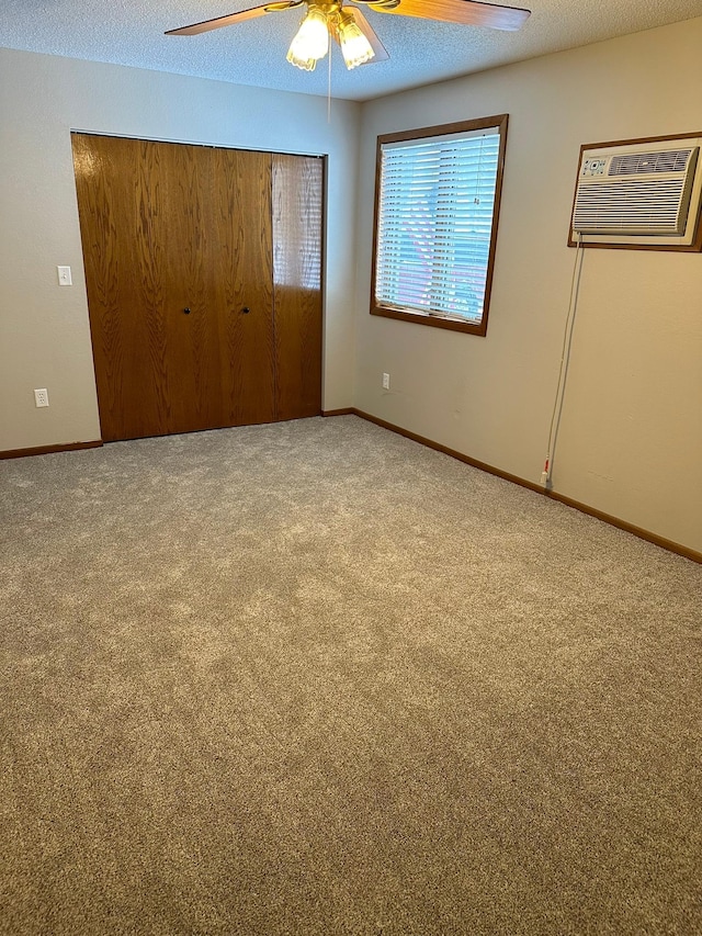 unfurnished bedroom featuring carpet flooring, ceiling fan, a wall unit AC, a textured ceiling, and a closet