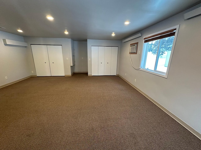 unfurnished bedroom featuring a wall unit AC, carpet, and two closets