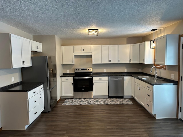 kitchen featuring white cabinets, decorative light fixtures, stainless steel appliances, and sink