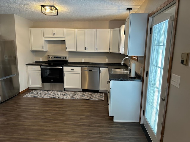 kitchen with white cabinets, appliances with stainless steel finishes, decorative light fixtures, and sink