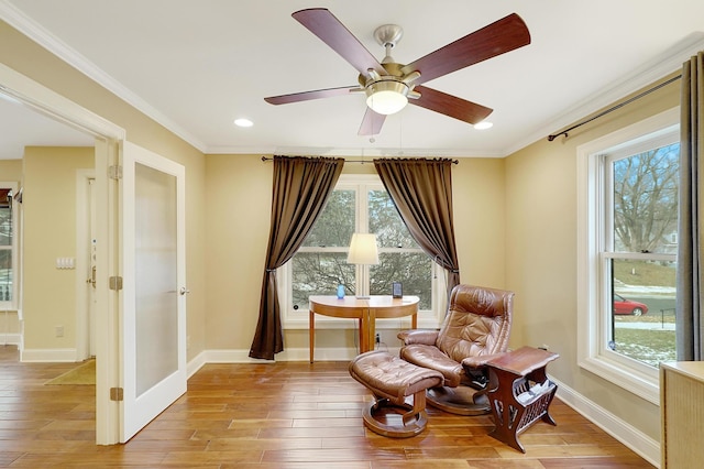 living area with light wood-type flooring, ceiling fan, and ornamental molding