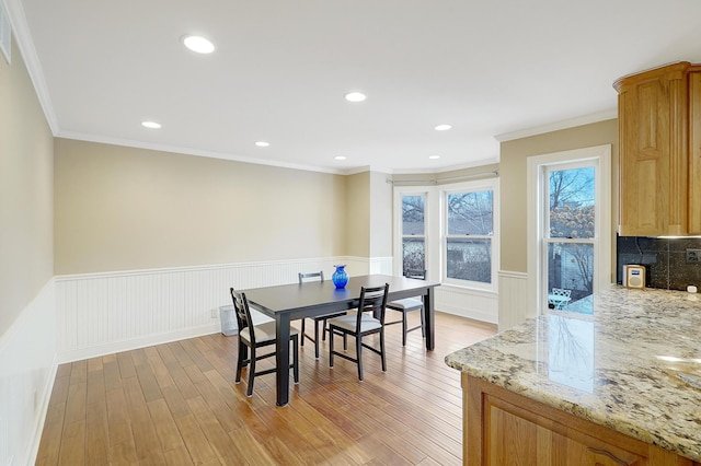 dining area with ornamental molding and light hardwood / wood-style floors