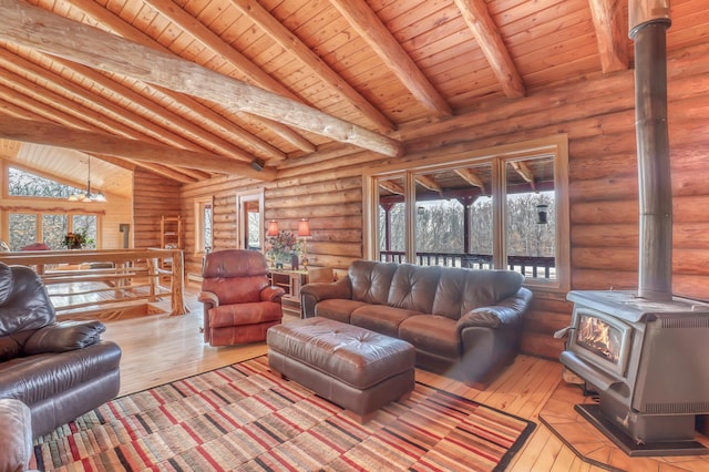 living room with a chandelier, vaulted ceiling with beams, light hardwood / wood-style floors, and a wood stove