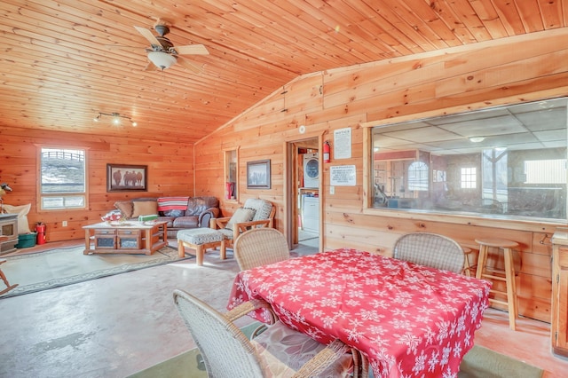 dining room with wood walls, lofted ceiling, a wealth of natural light, concrete flooring, and wood ceiling