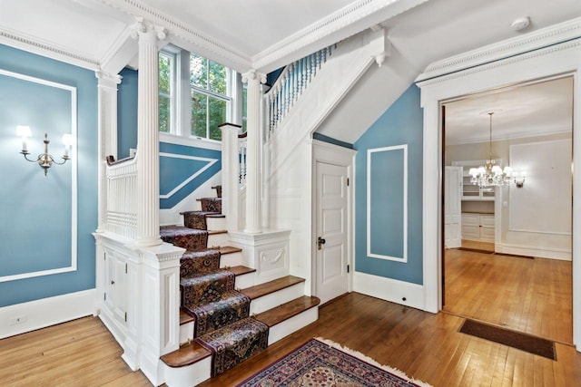 stairway featuring a notable chandelier, hardwood / wood-style floors, and ornamental molding