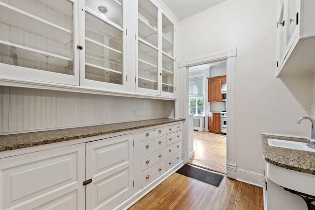 kitchen featuring white cabinets, dark stone counters, and sink