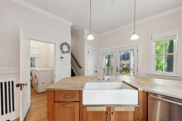 kitchen featuring sink, decorative light fixtures, stainless steel dishwasher, washer and clothes dryer, and crown molding