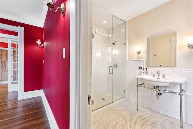 bathroom with hardwood / wood-style floors, crown molding, tile walls, sink, and an enclosed shower