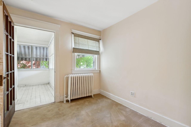 unfurnished room with radiator and light carpet