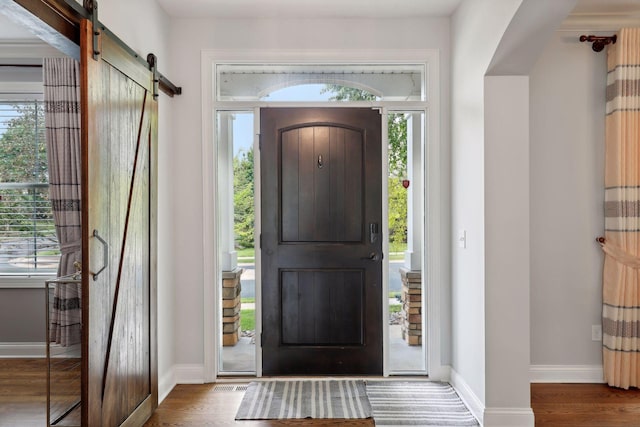 foyer entrance featuring a barn door, baseboards, and wood finished floors