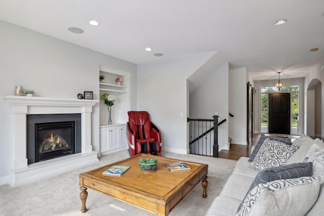 living room with built in features, a glass covered fireplace, baseboards, and recessed lighting