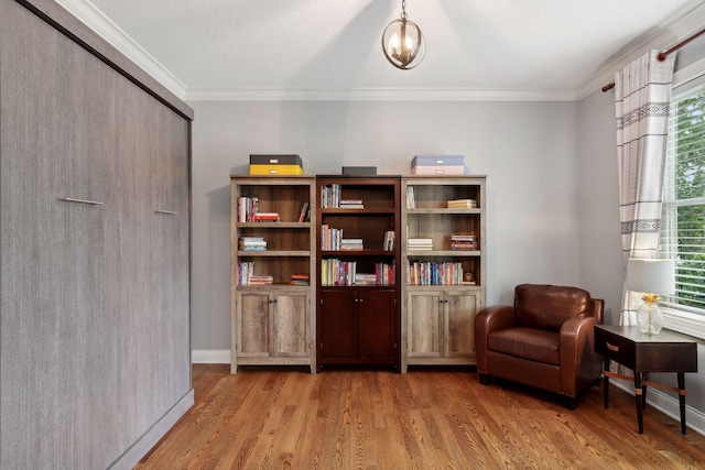 living area with light wood-style floors, baseboards, ornamental molding, and an inviting chandelier