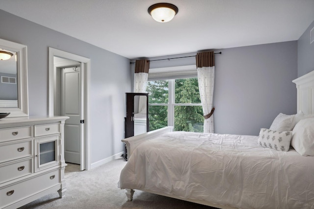 bedroom with baseboards, visible vents, and light colored carpet