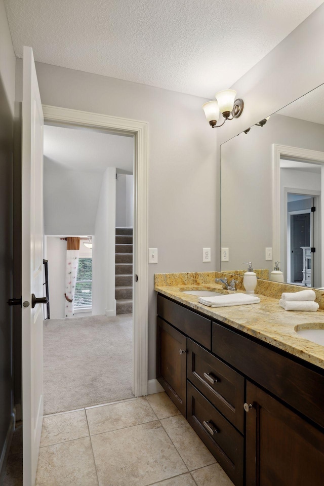 full bath with double vanity, a textured ceiling, and a sink