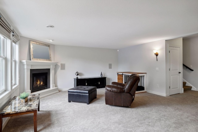 living area with carpet floors, a lit fireplace, stairway, and baseboards