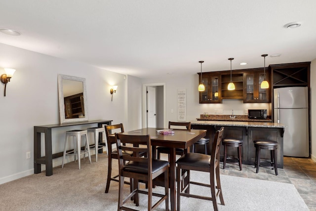 dining space featuring light carpet, wet bar, and baseboards