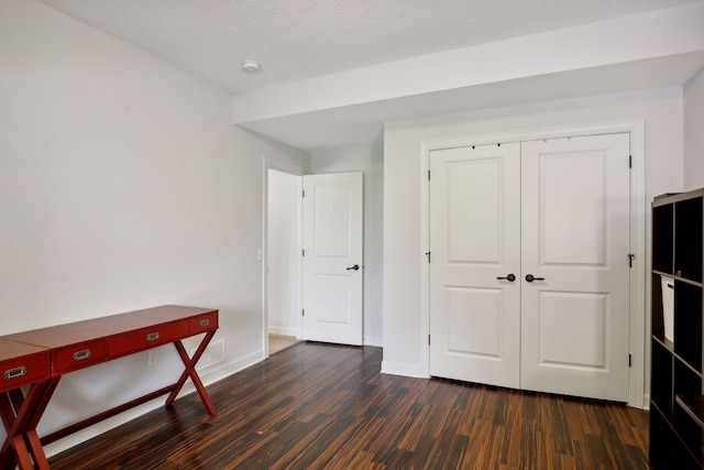 bedroom featuring dark wood-style floors, a closet, baseboards, and a textured ceiling