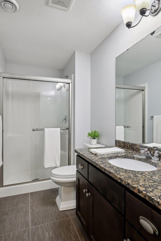 full bath featuring a stall shower, visible vents, toilet, a textured ceiling, and vanity